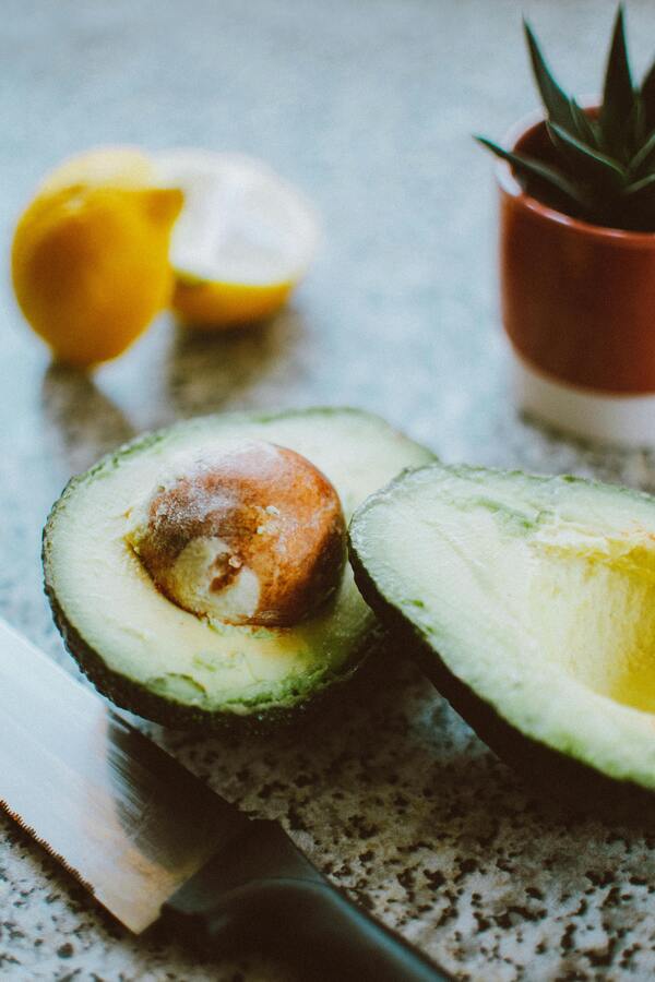 A food processor blending avocados, basil, and other ingredients into a smooth, creamy green sauce.