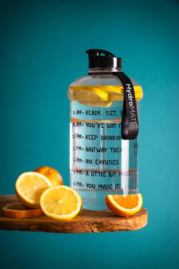 A person drinking a refreshing glass of water with lemon and mint.