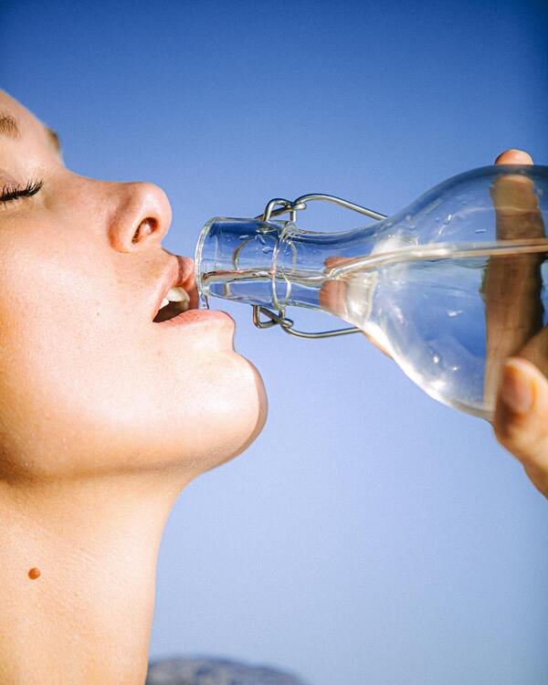 A person looking tired and holding their head, illustrating the symptoms of dehydration.