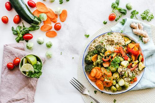 A vibrant plate of keto-friendly foods including salmon, avocado, leafy greens, and nuts.