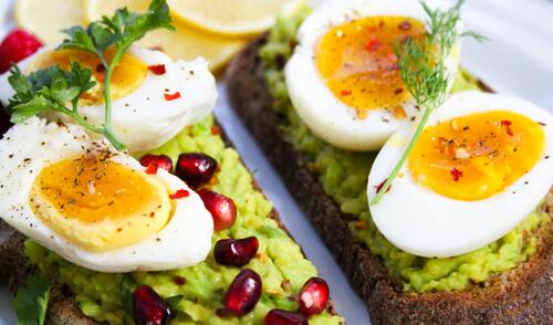 Assorted Indian keto ingredients like paneer, eggs, leafy greens, nuts, seeds, and oils